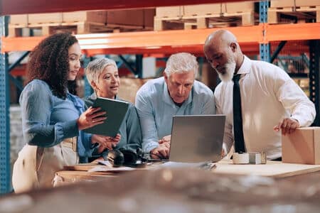 A logistics team standing around a laptop strategizing