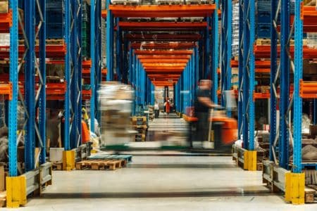 Forklifts Moving Through Busy Warehouse Aisle.