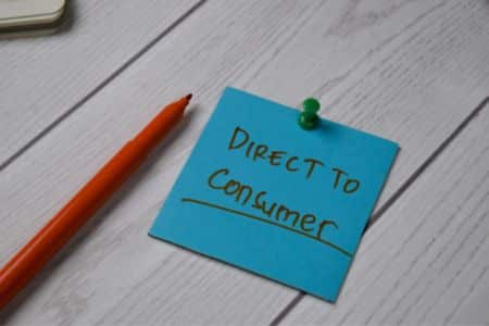 direct-to-consumer business concept written on a note beside office supplies.