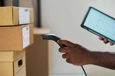 warehouse employee scanning inventory with a barcode scanner and tablet.